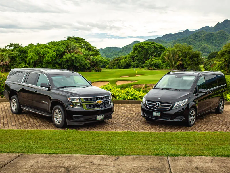 Black Chevrolet Suburban and a black Mercedes van parked by a golf course