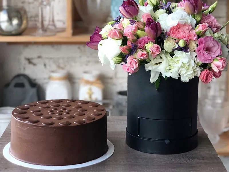 Chocolate cake beside a box of pink and white flowers