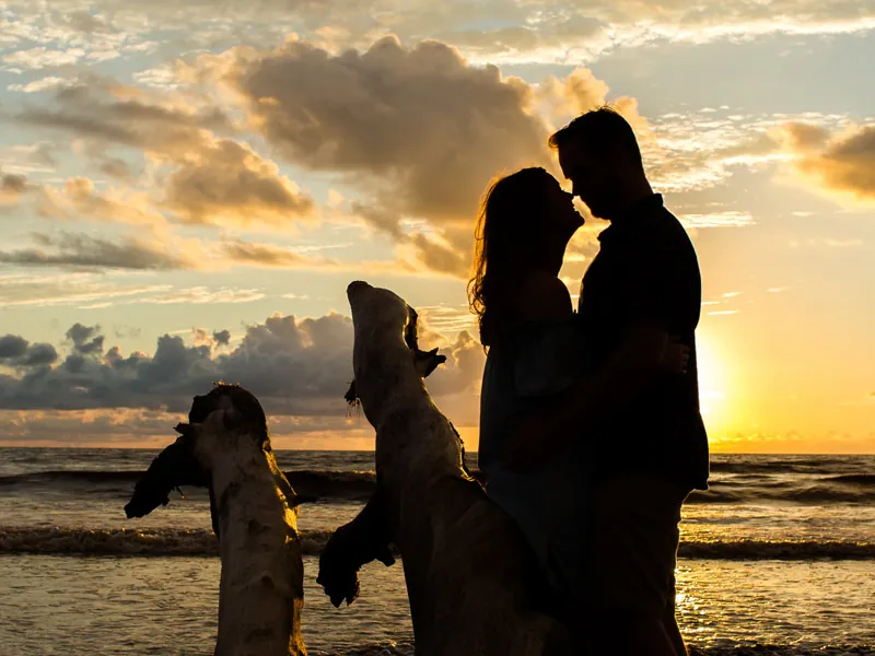 Couple embracing at sunset on the beach with a dog