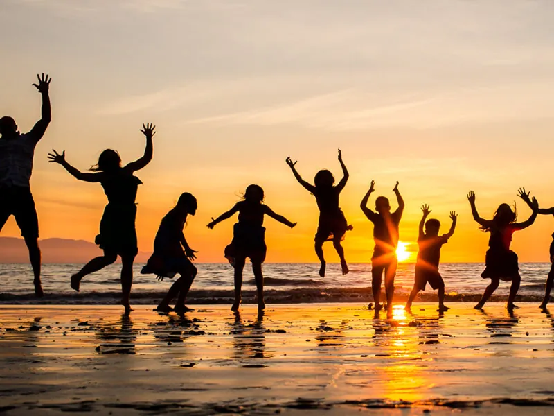 Group of friends jumping on the beach at sunset