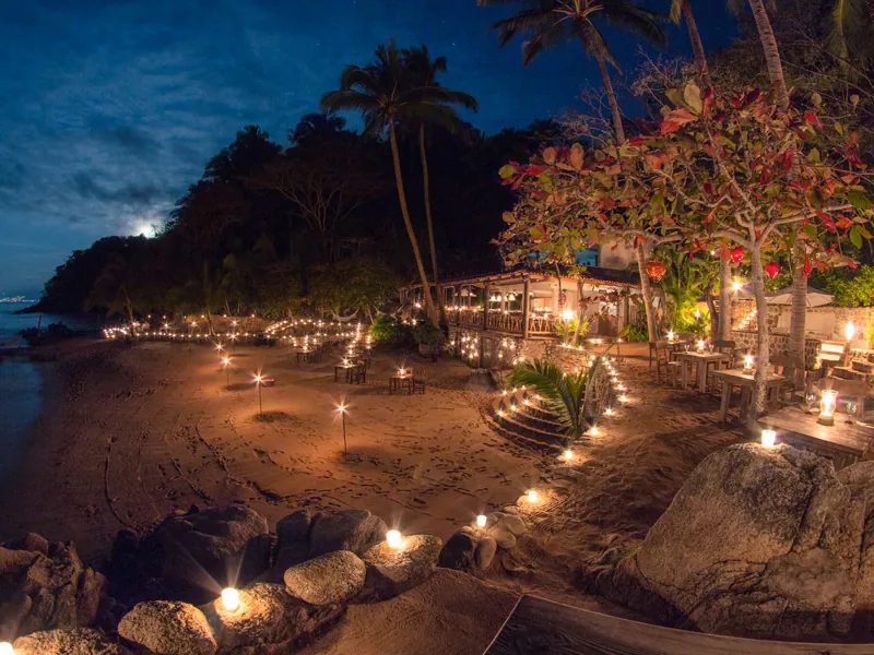 Torch-lit cove of Las Caletas at night, lanterns along the shore