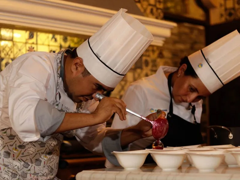 Two chefs finishing plates with a garnish