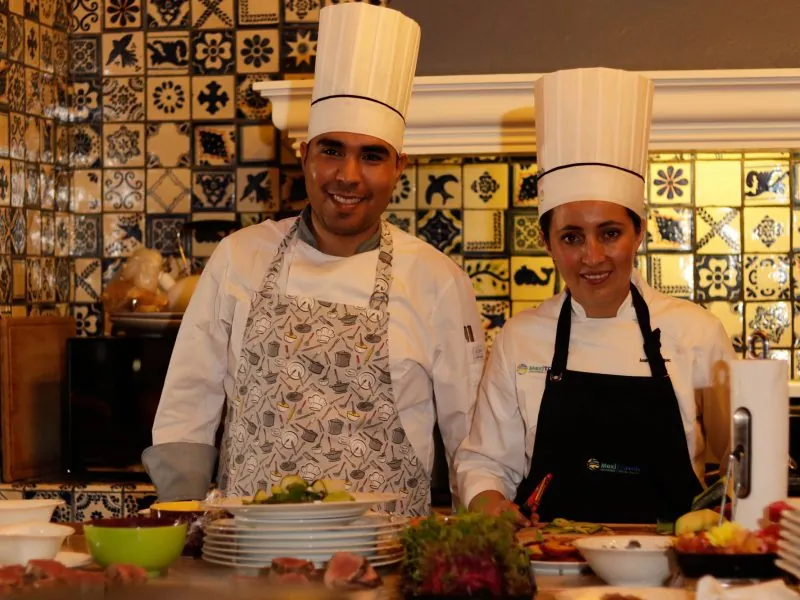 Two chefs presenting dishes at a kitchen counter