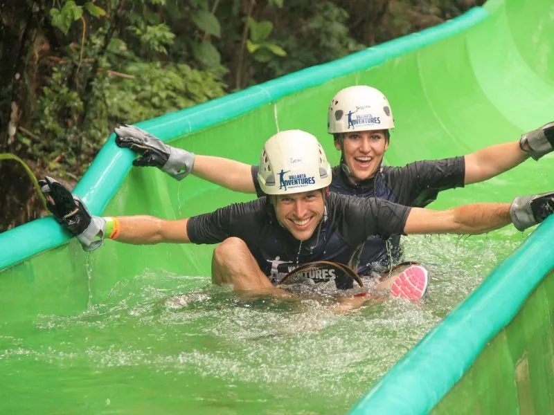 Two guests in helmets splashing down a water slide