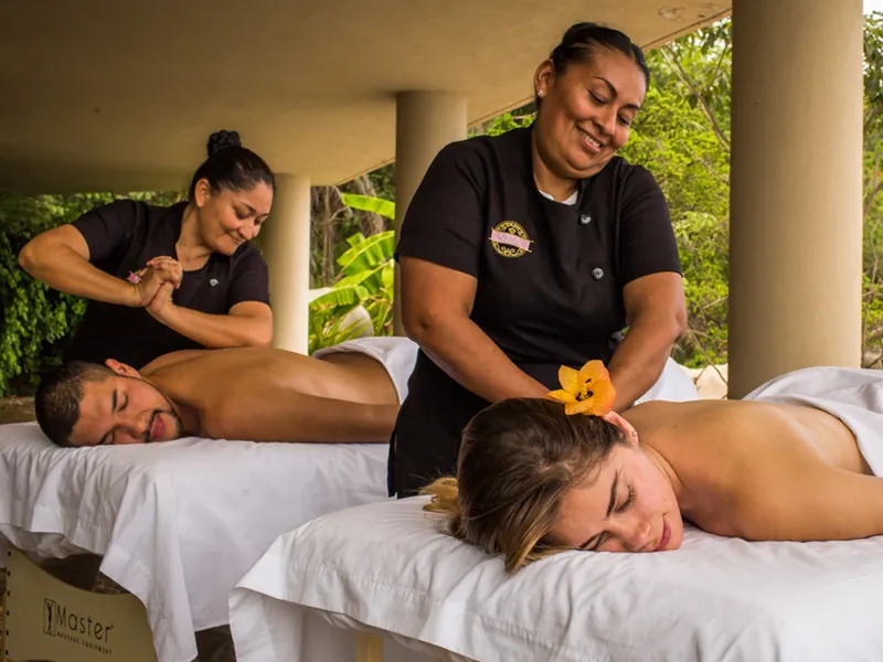 Two therapists giving a couples massage on a villa terrace